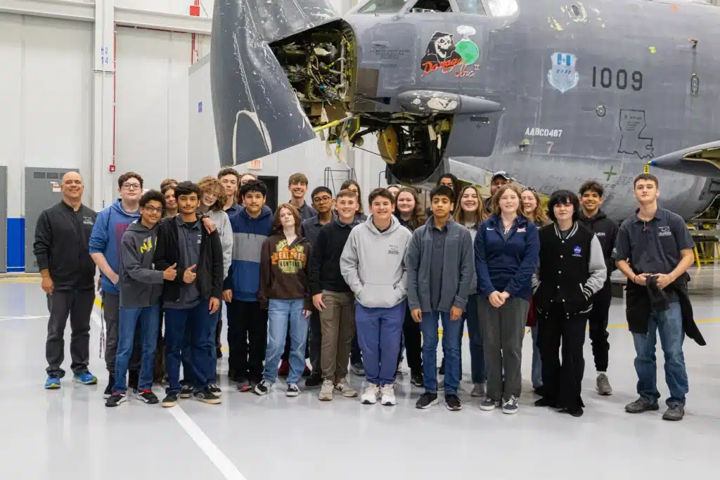 Students and instructors pose in front of an aircraft during a Boeing Aerospace Week visit.