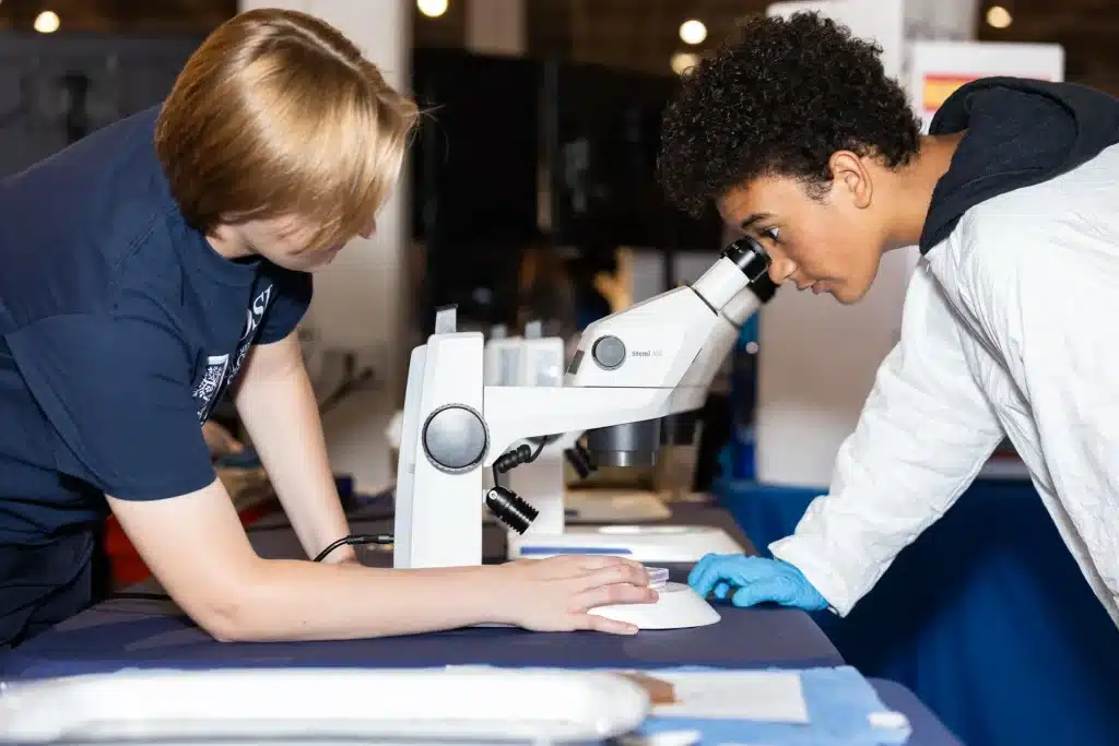 Two students examine a sample through a microscope during Innovation Week.