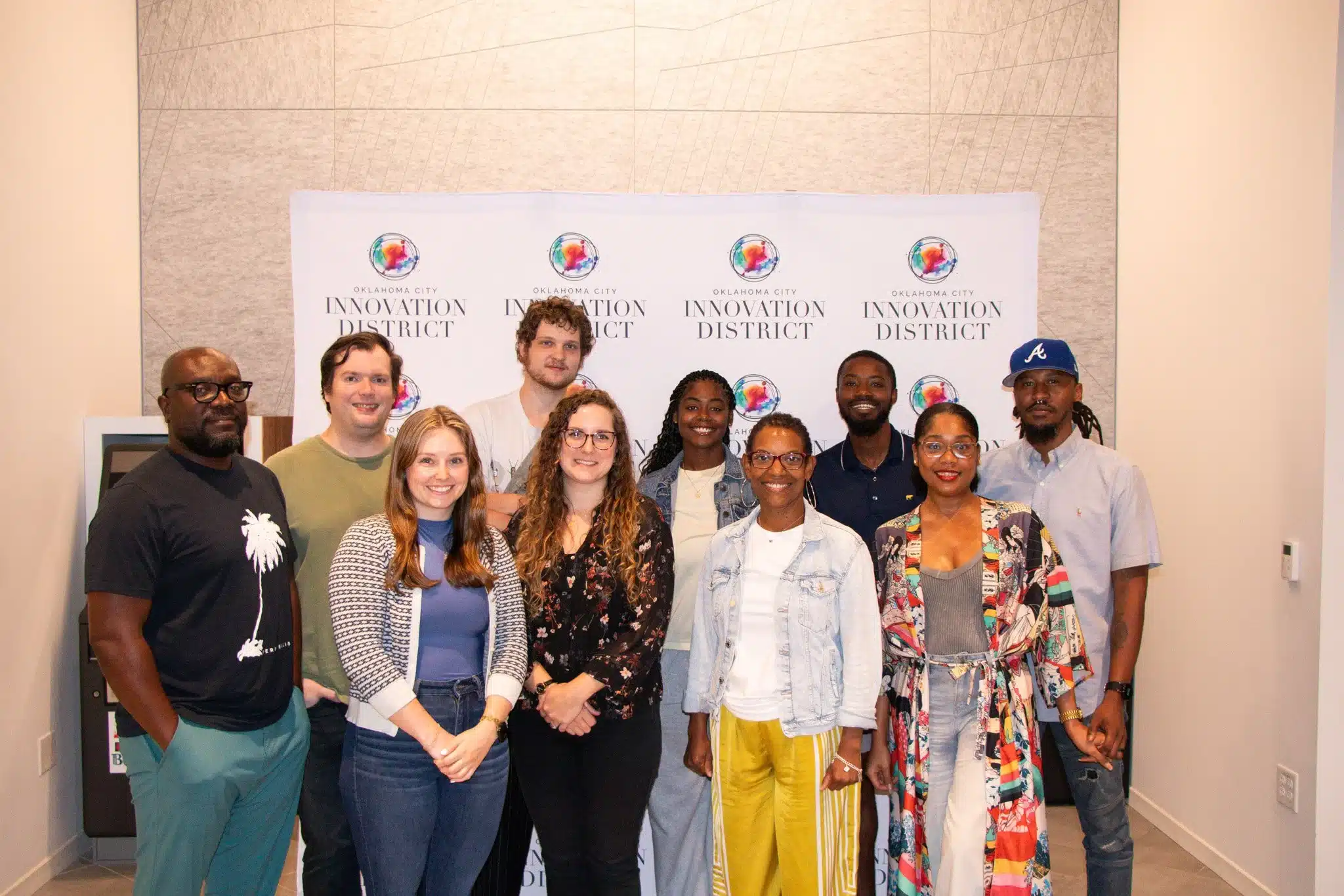 Startup OU Idea Accelerator participants pose together in front of an Oklahoma City Innovation District backdrop.