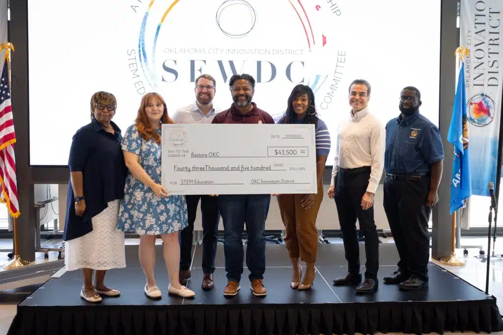 Grant recipients and OKCID representatives hold an oversized check at a STEM education funding presentation.