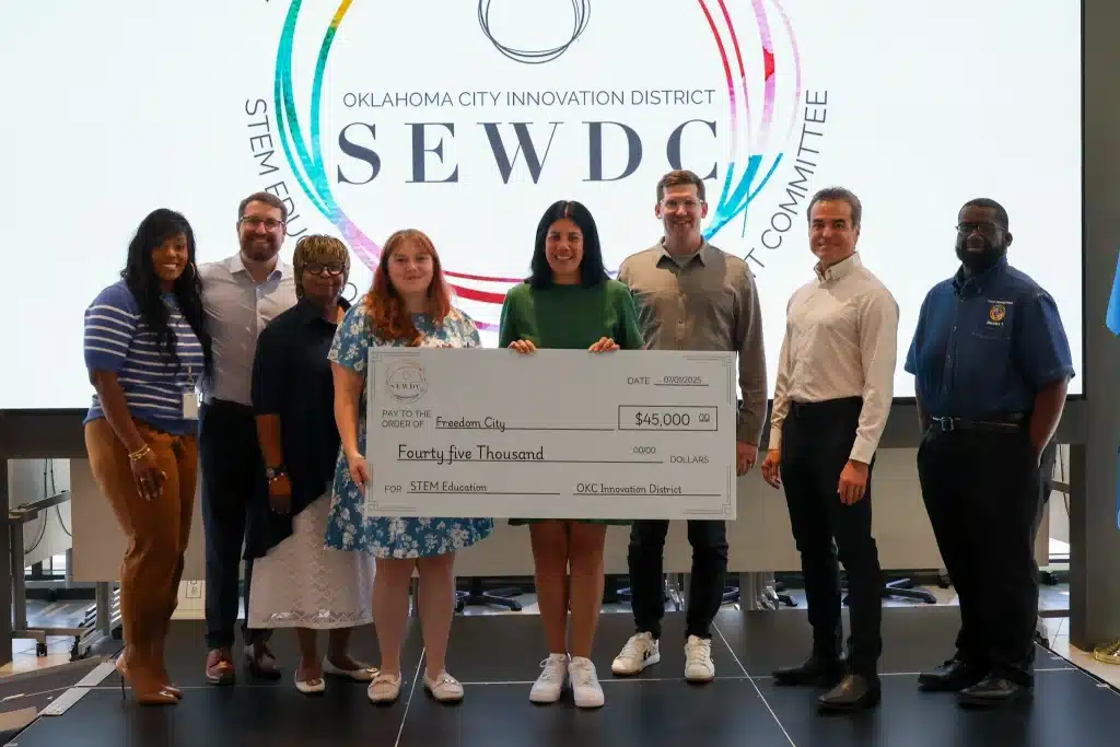 A group of grant recipients holds an oversized $45,000 check at an OKCID STEM education funding presentation.