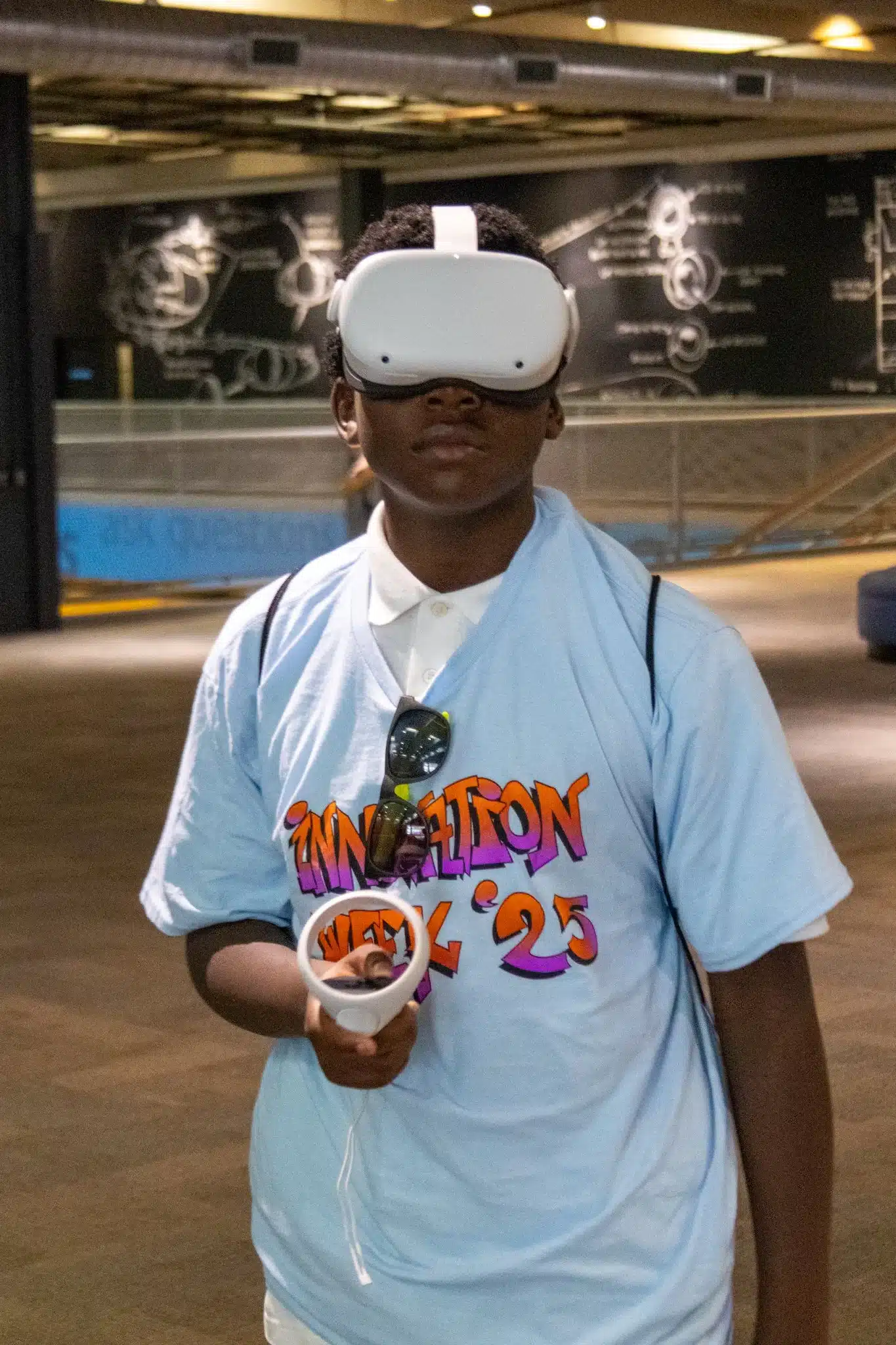 A student tries a virtual reality headset and handheld controller during Innovation Week 2025.