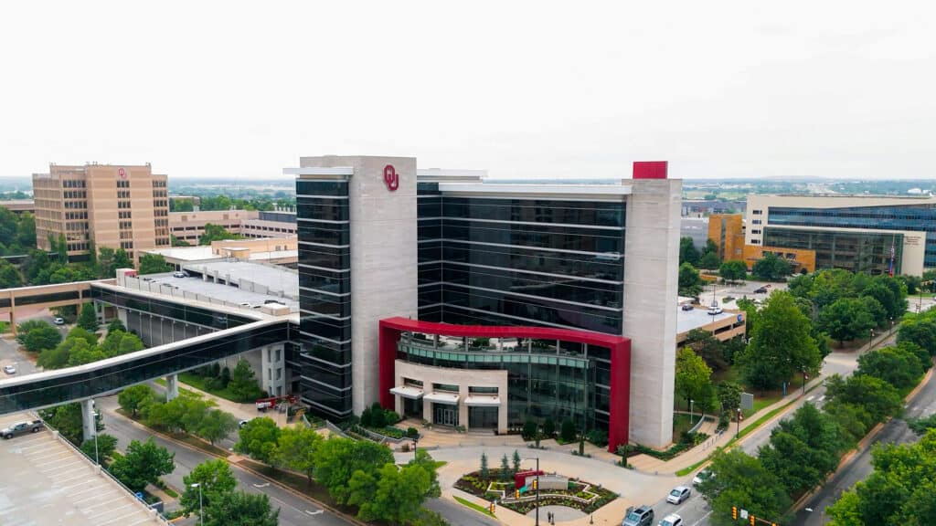 Aerial view of an OU Health medical building with glass façades and enclosed pedestrian bridges.