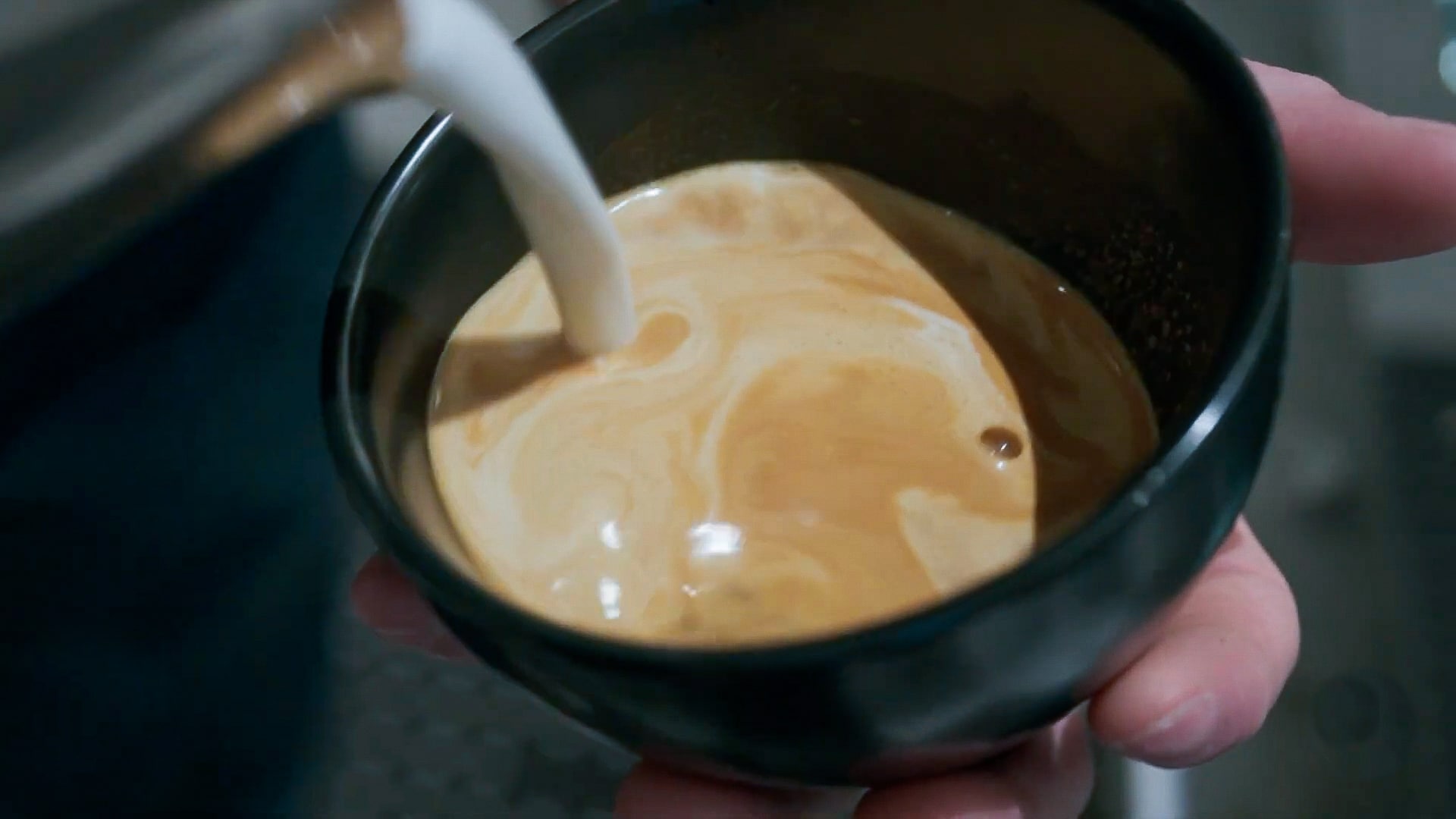 Steamed milk is poured into a cup of espresso to make a latte.
