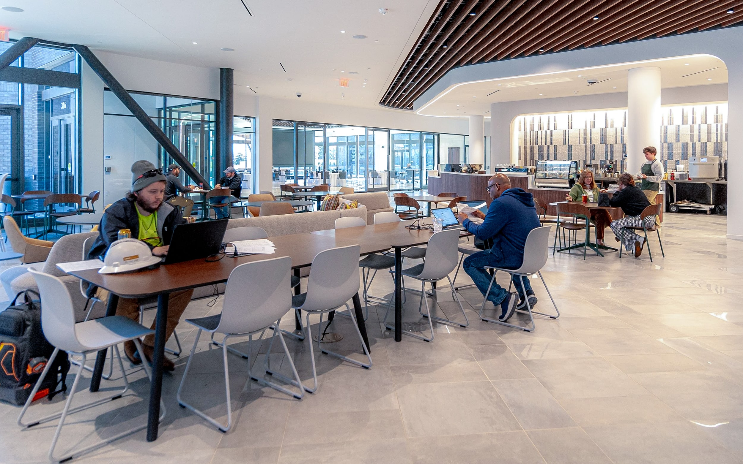 Visitors work and talk at café tables beside the Elemental Coffee counter inside Innovation Hall.