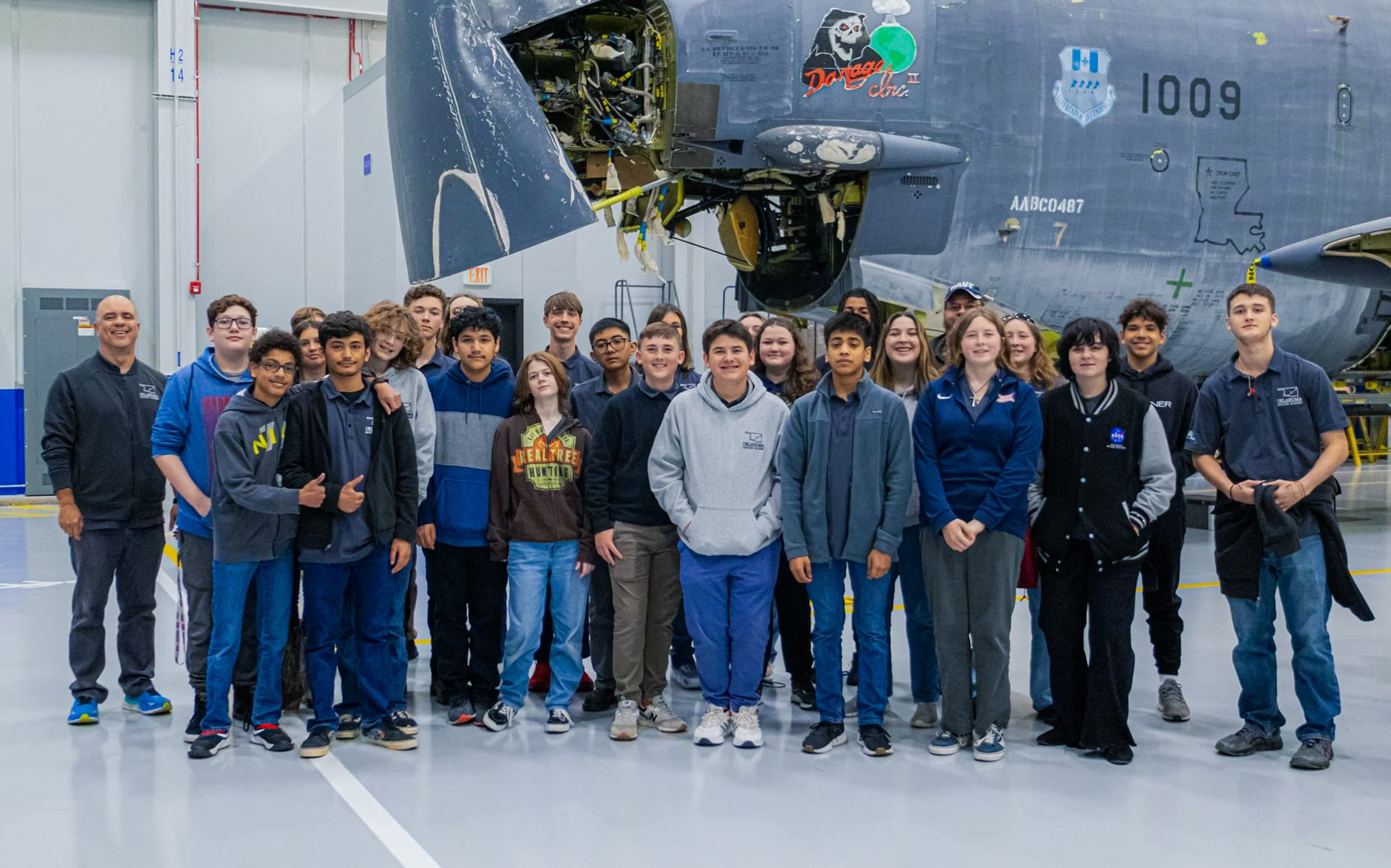 Students and instructors pose in front of an aircraft during an Aerospace Week visit.