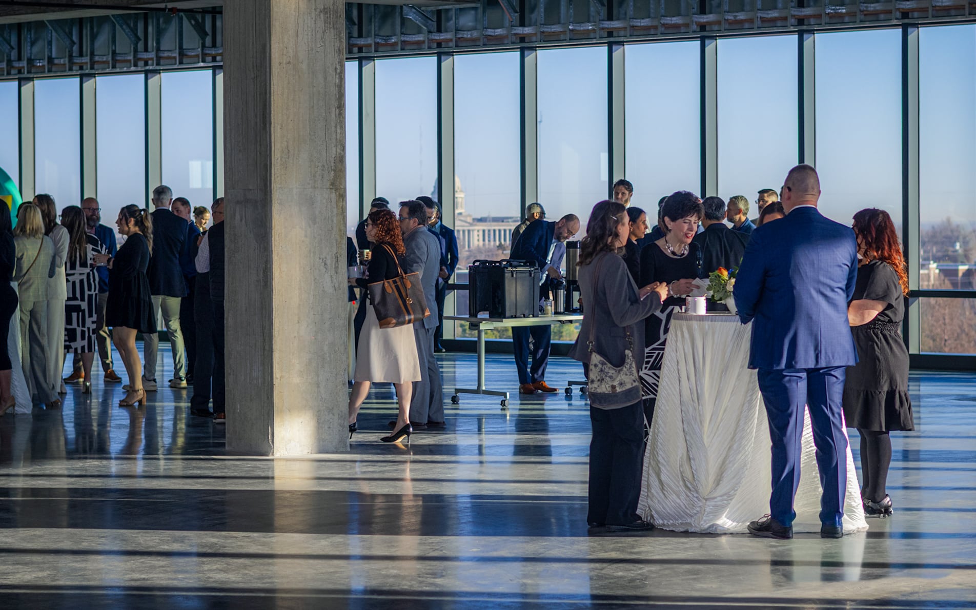 Guests gather beside floor-to-ceiling windows for a networking event.