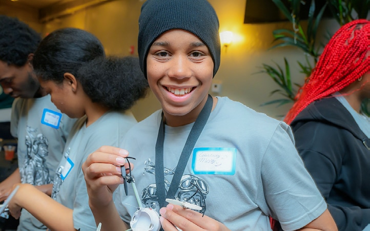 A smiling student holds a small science project during Innovation Week.