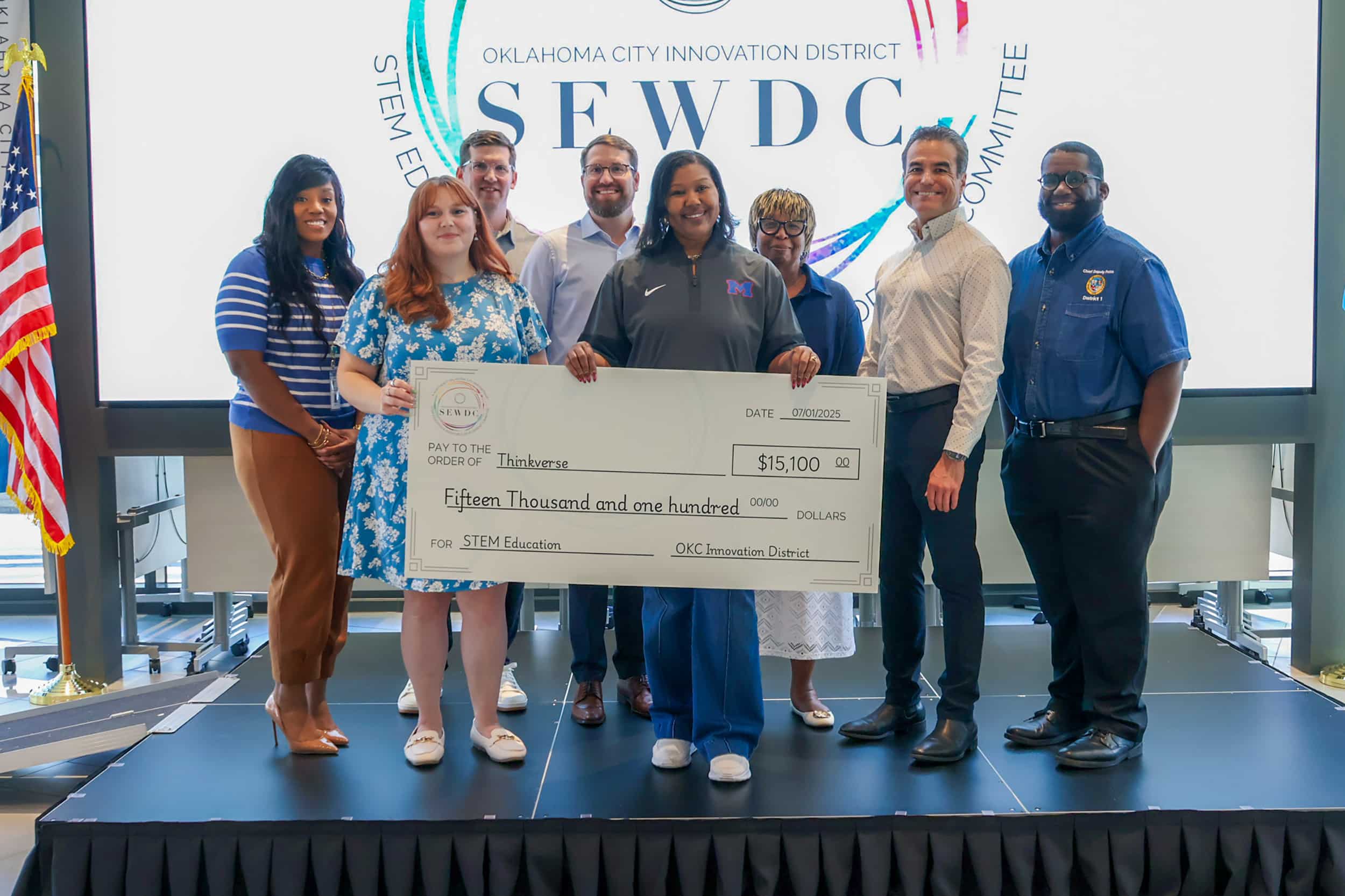STEM education grant recipients hold an oversized $15,100 check at an Oklahoma City Innovation District presentation.