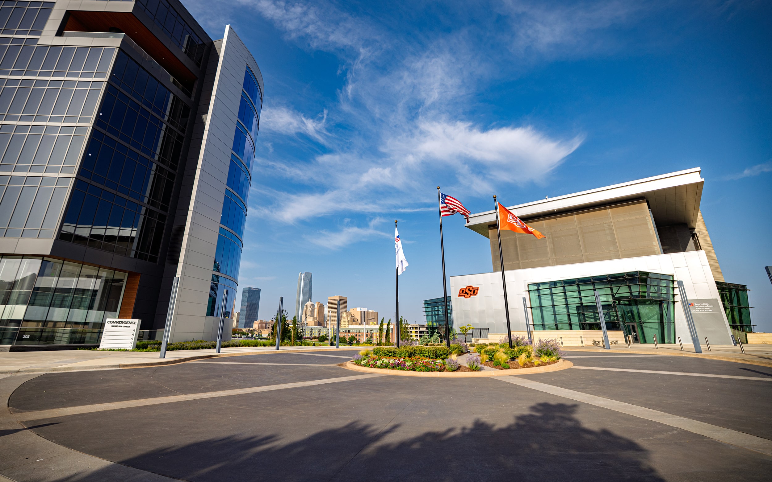 Entrance to the Hamm Institute for American Energy with flags and the Oklahoma City skyline beyond.
