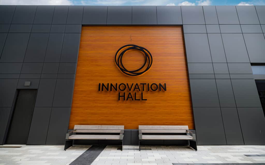 Innovation Hall sign mounted on a wood-paneled exterior wall above outdoor benches.