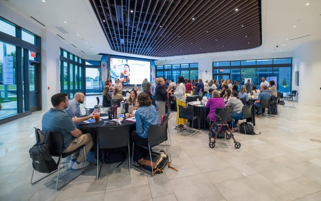 Guests seated around banquet tables for a presentation inside Innovation Hall.