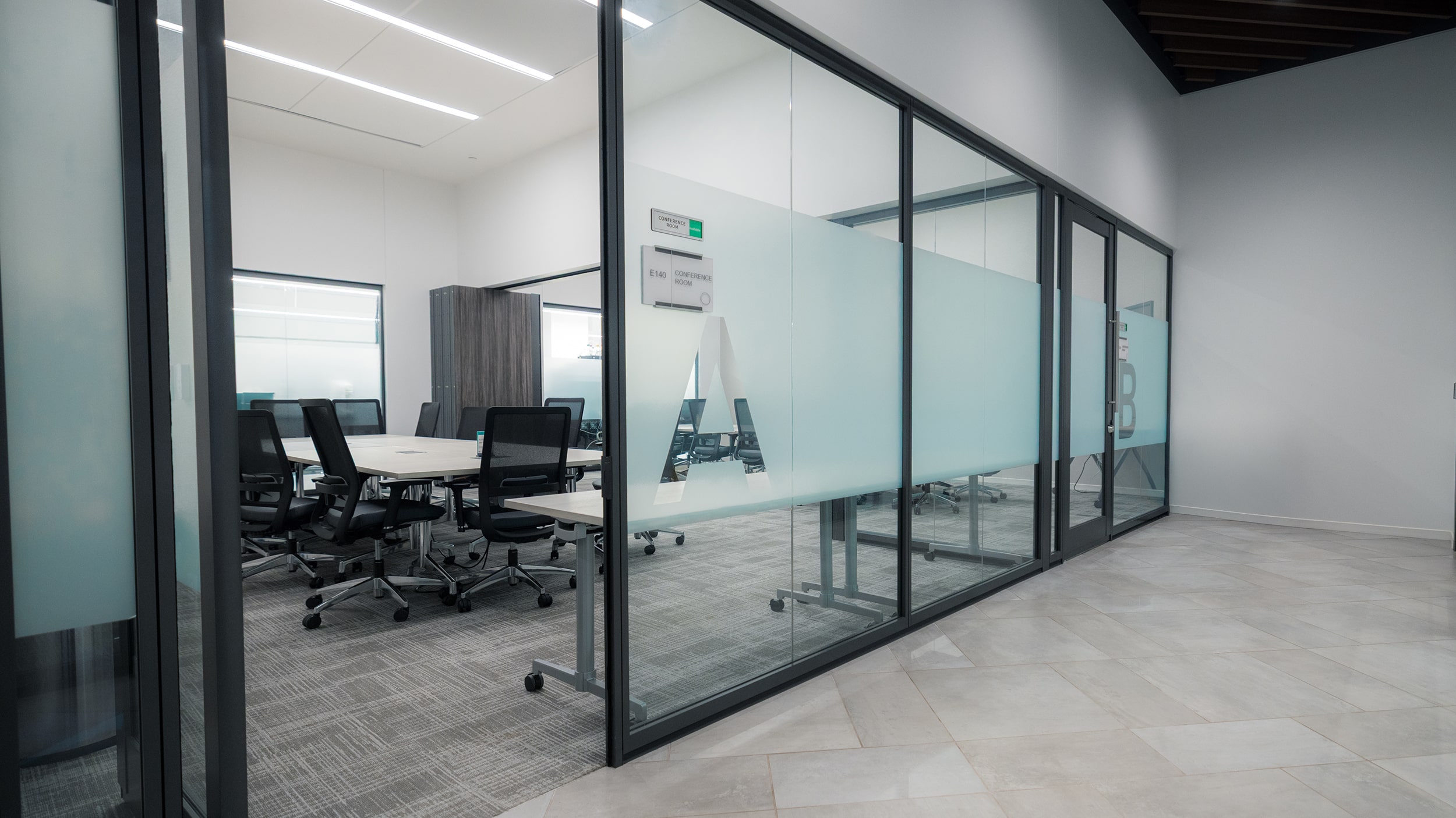 Glass-walled conference room at Innovation Hall with a whiteboard, table, and rolling chairs.