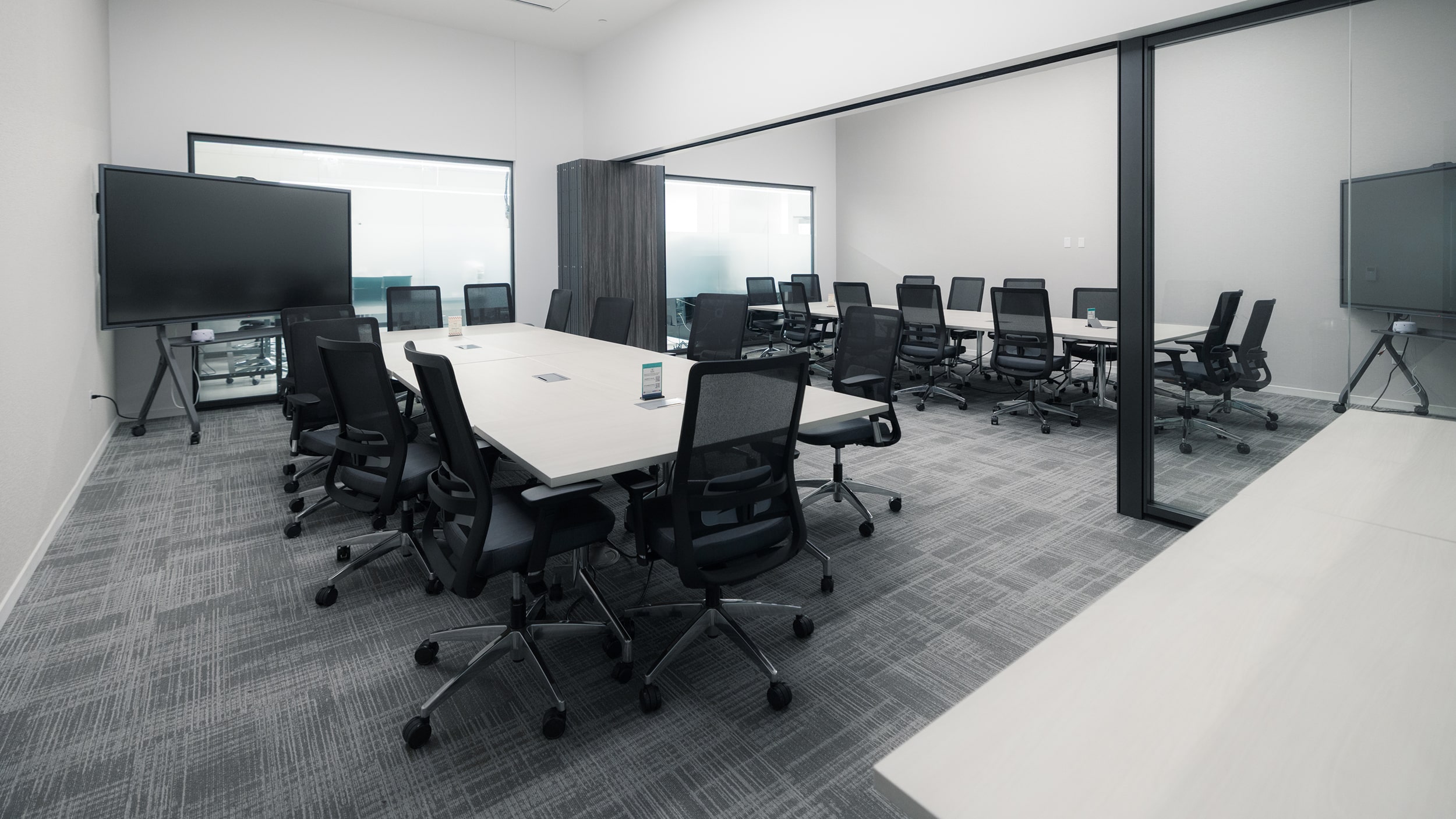 Innovation Hall conference rooms with tables, rolling chairs, and large display monitors.