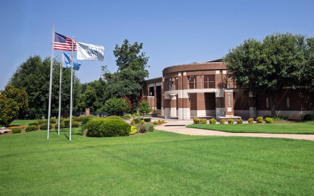 Oklahoma School of Science and Mathematics campus with flags, trees, and a lawn.